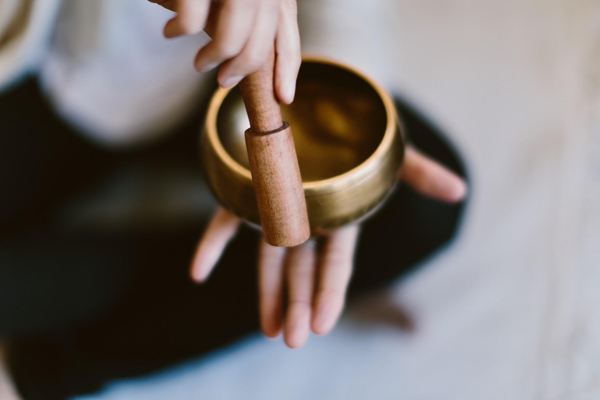 Angle shot of a woman using a Tibetan meditation singing bowl.