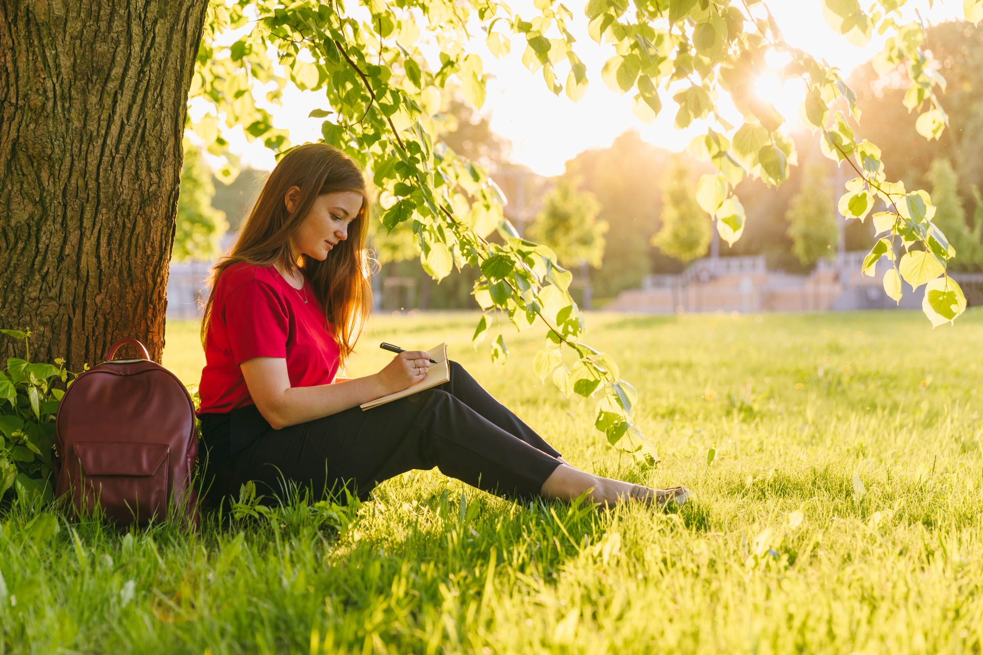 Girl sitting in the summer park and planning her goals and ways with notes. Life coach goals concept